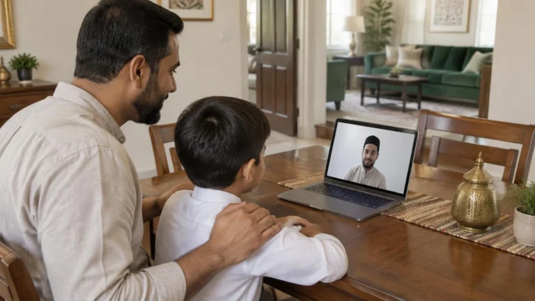 A father and his son at a table during an online Quran lesson with the teacher on a laptop