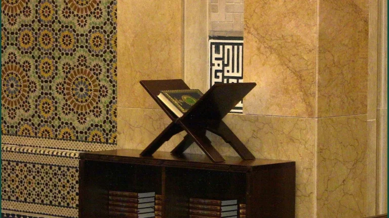 A Quran on a wooden stand in a mosque beside shelves of books